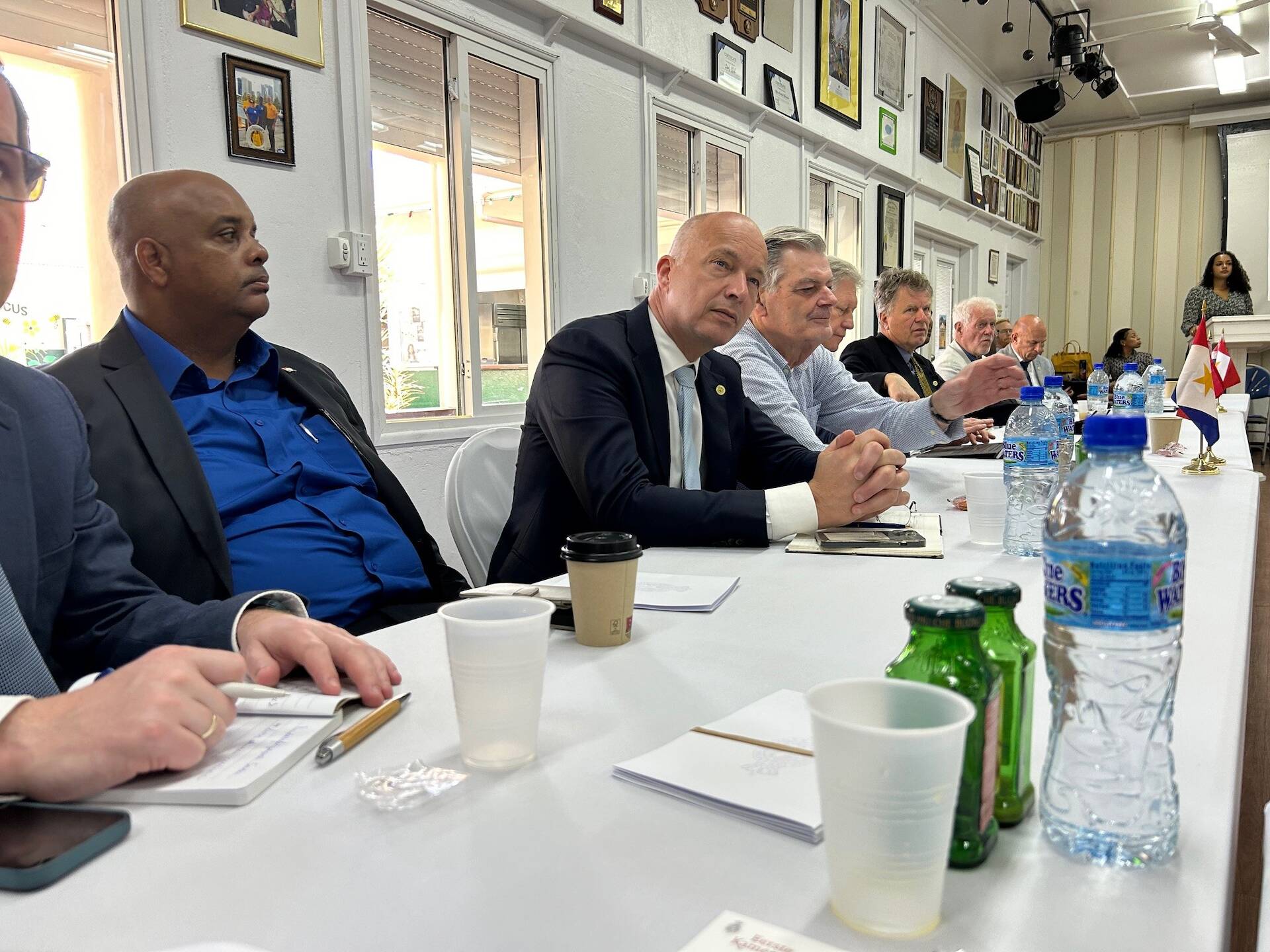 Een groep mensen is aan een rechthoekige tafel met elkaar in gesprek