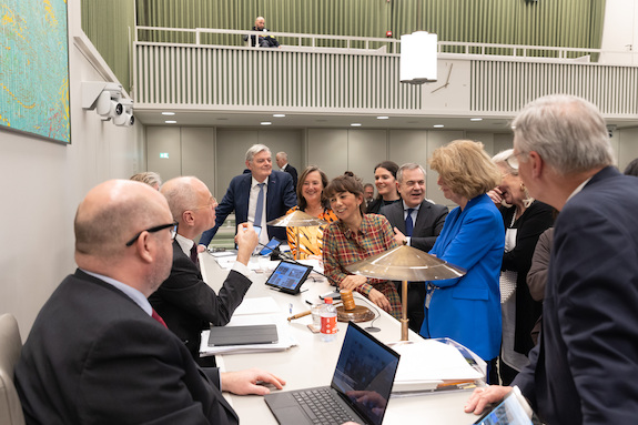 De woordvoerders van het debat overleggen bij het rostrum met de Voorzitter