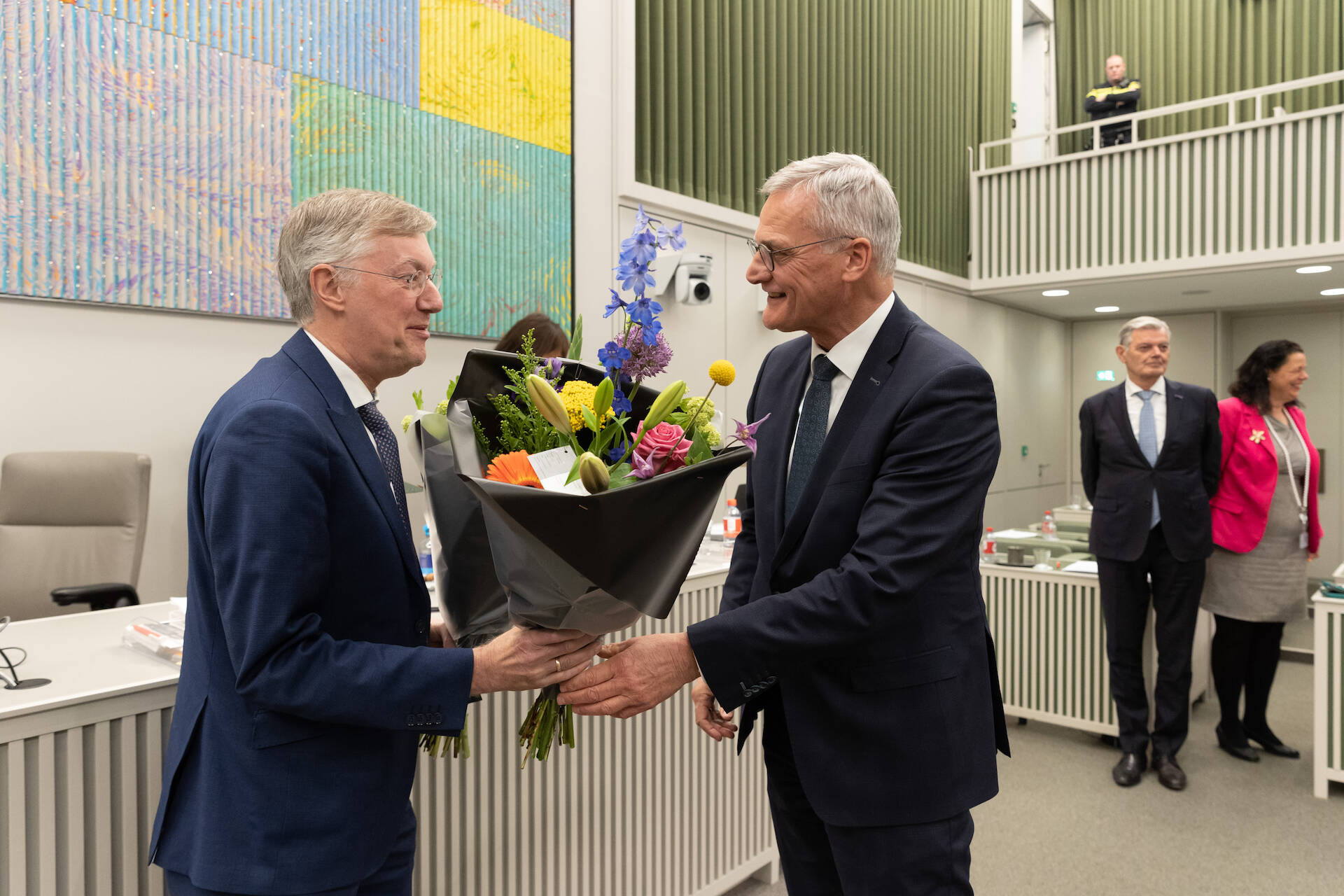 Foto van senator Schalk die een bos bloemen aan De Vries geeft